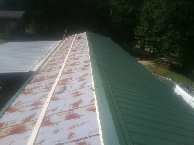 Old rusted panels beside newly installed green metal roofing — Wind Damage Roof Repair by Roofing Brothers in New Melle