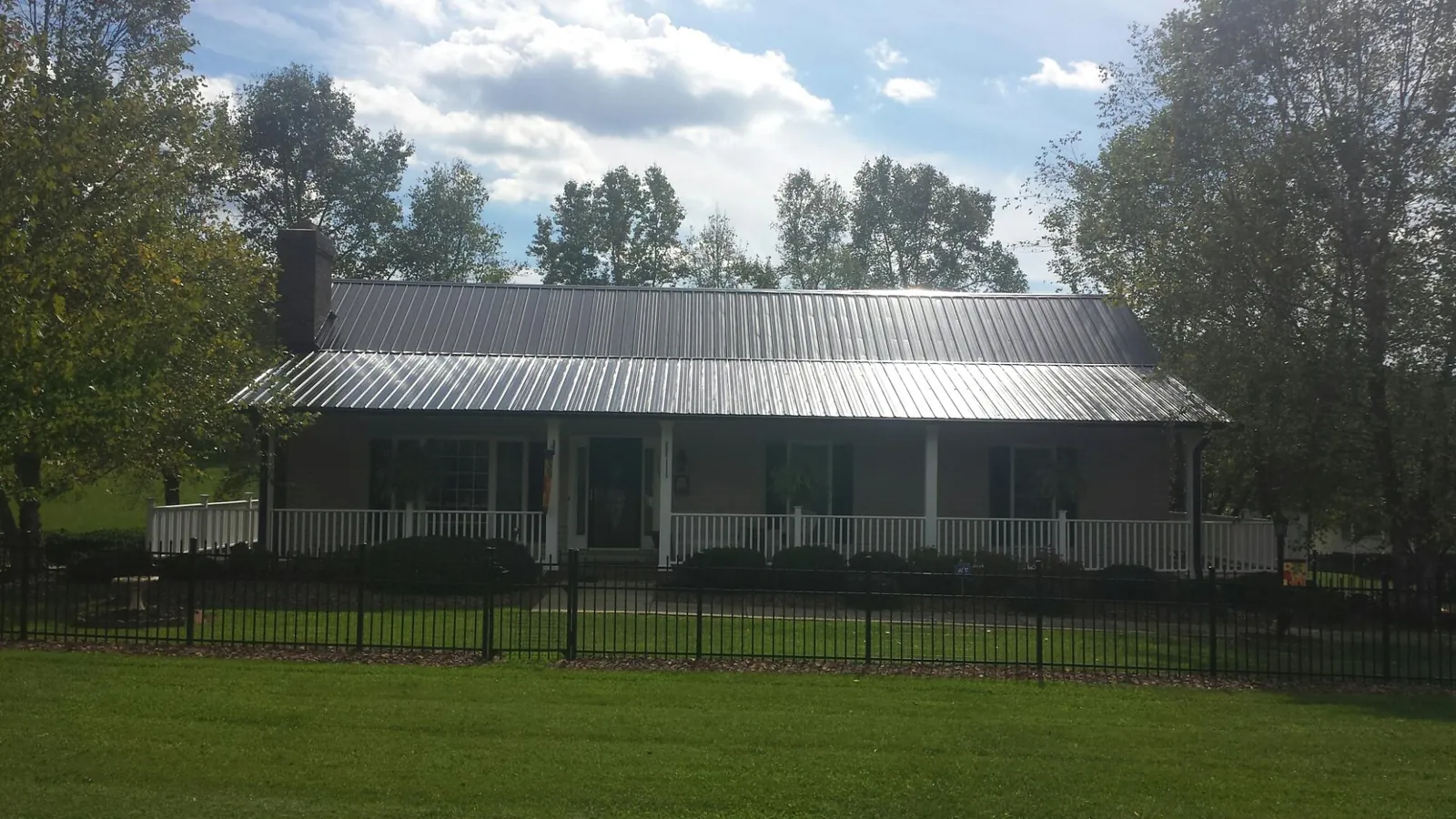 Gray metal roof on a brick ranch with a full width front porch — Gutter Guard Installation work by our crew in New Melle