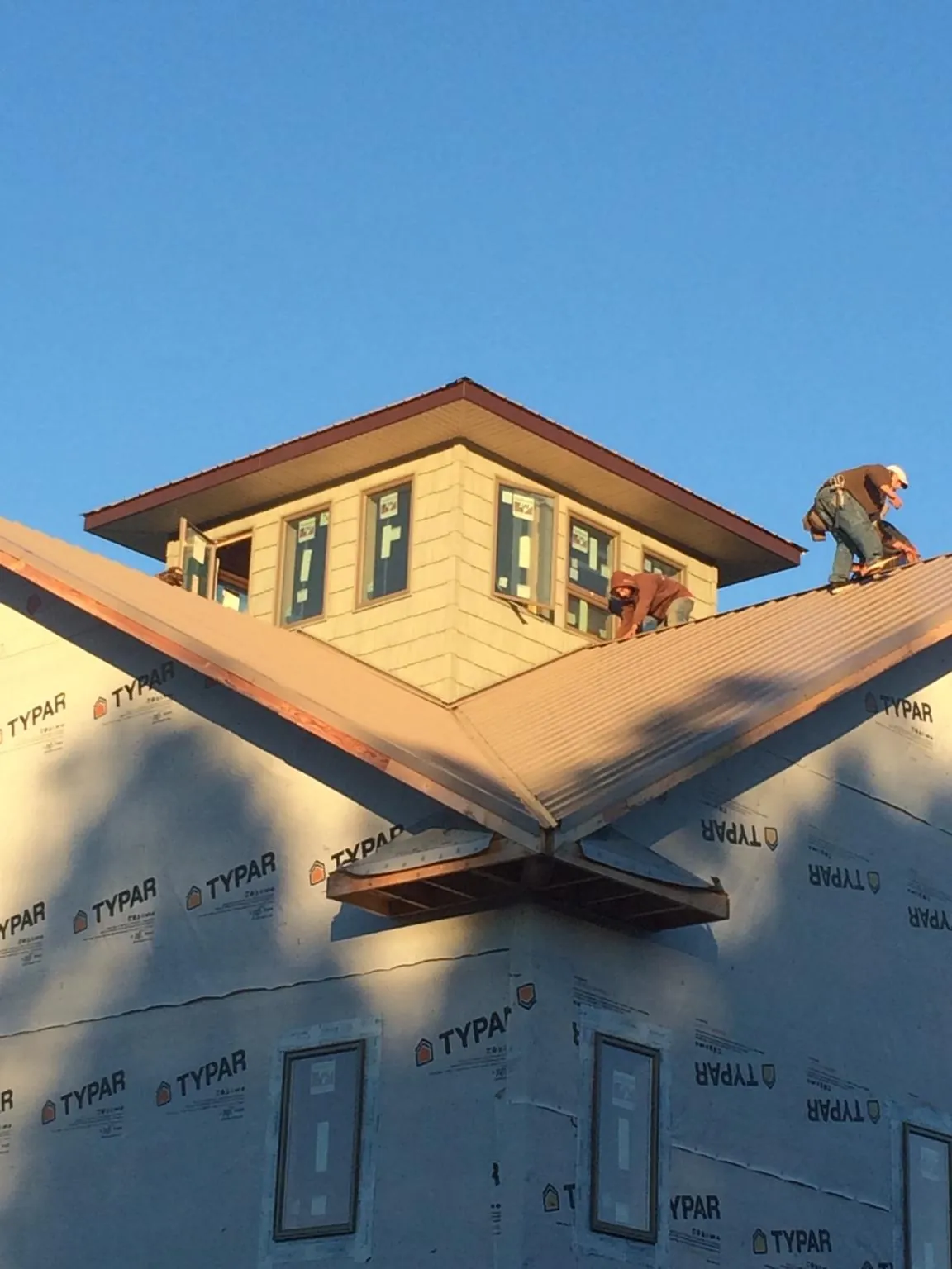Roofers working around a rooftop cupola on a new metal roof at sunset — Roof Waterproofing in New Melle by Roofing Brothers